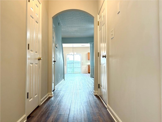 3884 Grovemont Pl, Duluth, GA 30096 - hall with arched walkways, dark wood-style floors, a textured ceiling, and a chandelier