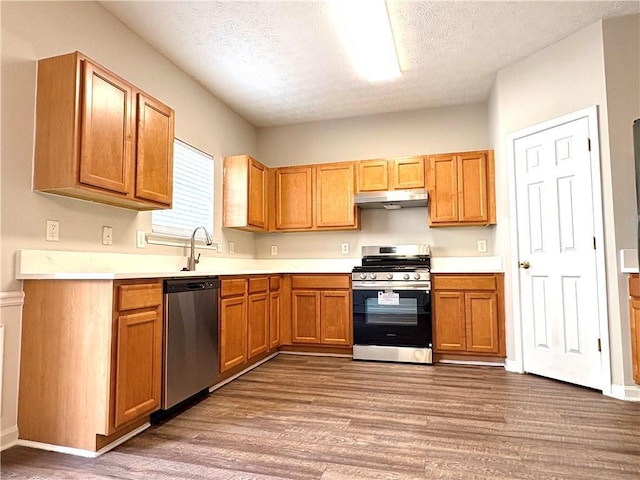 3884 Grovemont Pl, Duluth, GA 30096 - kitchen featuring stainless steel appliances, under cabinet range hood, wood finished floors, a textured ceiling, and light countertops