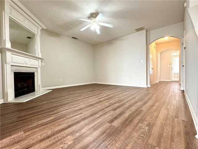 3884 Grovemont Pl, Duluth, GA 30096 - unfurnished living room featuring ceiling fan, wood finished floors, arched walkways, and a fireplace with raised hearth