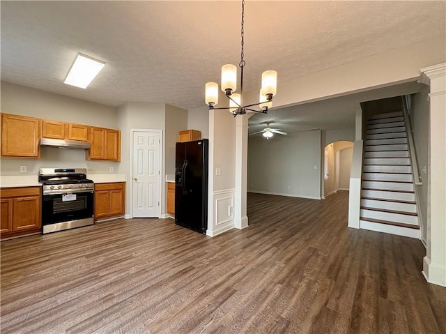 3884 Grovemont Pl, Duluth, GA 30096 - kitchen featuring stainless steel range with gas stovetop, black fridge, under cabinet range hood, dark wood-style flooring, and arched walkways