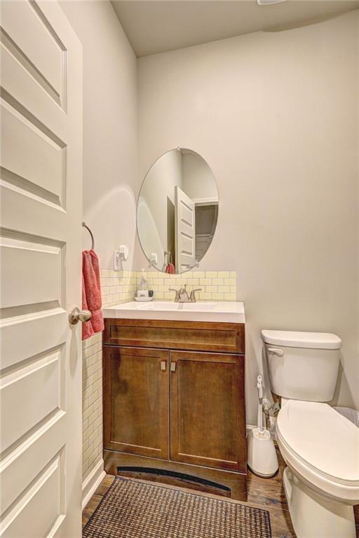 bathroom featuring decorative backsplash, vanity, hardwood / wood-style flooring, and toilet