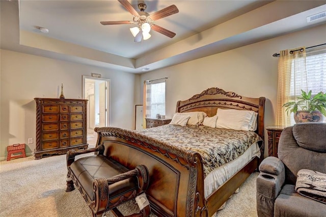 bedroom with ceiling fan, carpet floors, and a tray ceiling