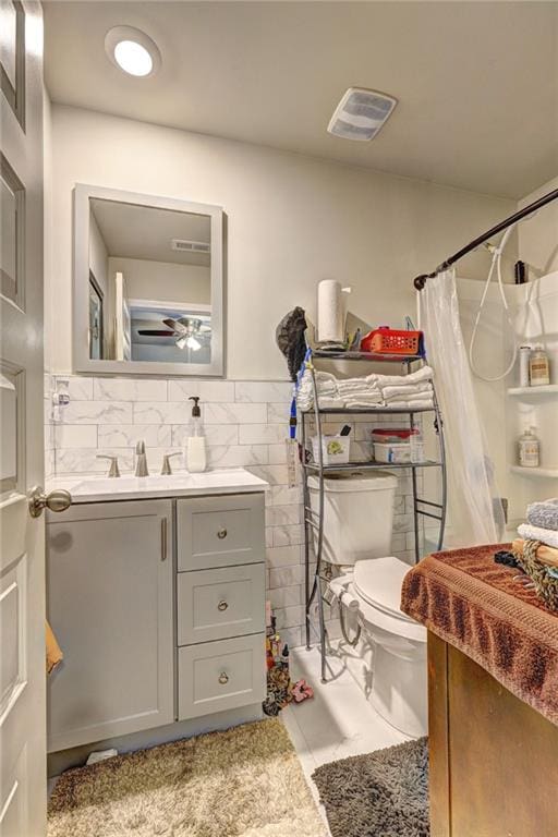 bathroom with a shower with curtain, vanity, toilet, and ceiling fan