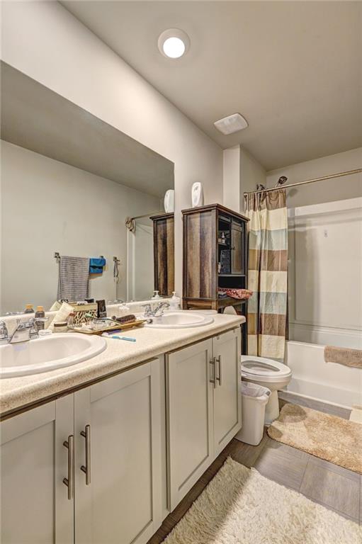 full bathroom with shower / bathtub combination with curtain, vanity, and toilet