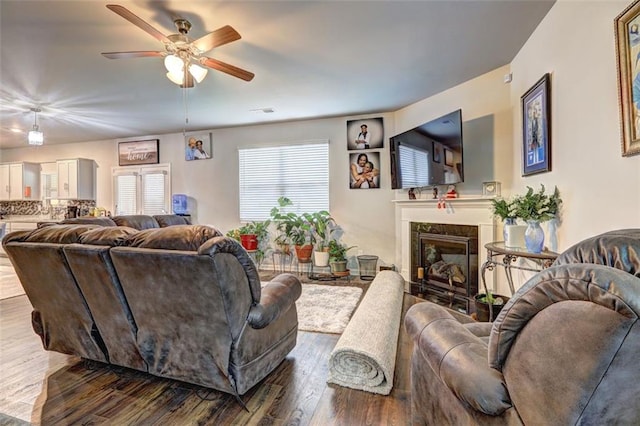 living room featuring ceiling fan, a high end fireplace, and wood-type flooring