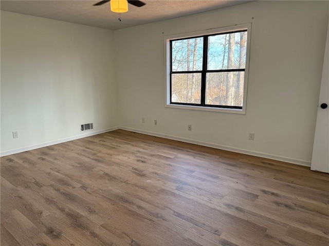 unfurnished room featuring baseboards, ceiling fan, visible vents, and wood finished floors