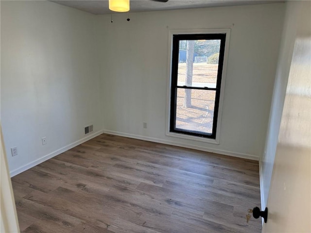 spare room with visible vents, baseboards, and wood finished floors