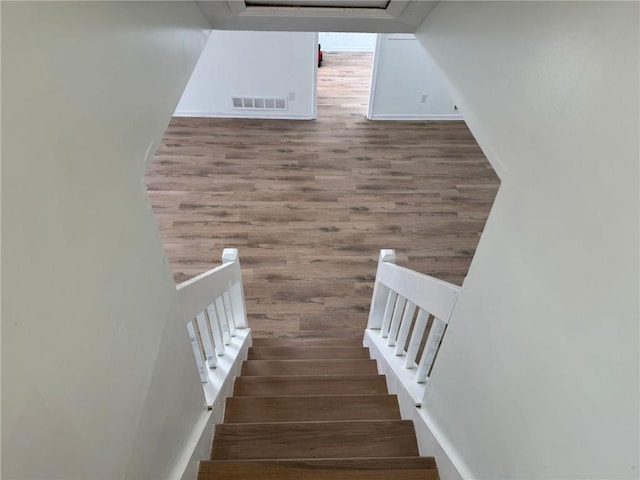 stairway featuring visible vents and wood finished floors