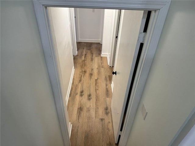 corridor featuring wood finished floors and baseboards