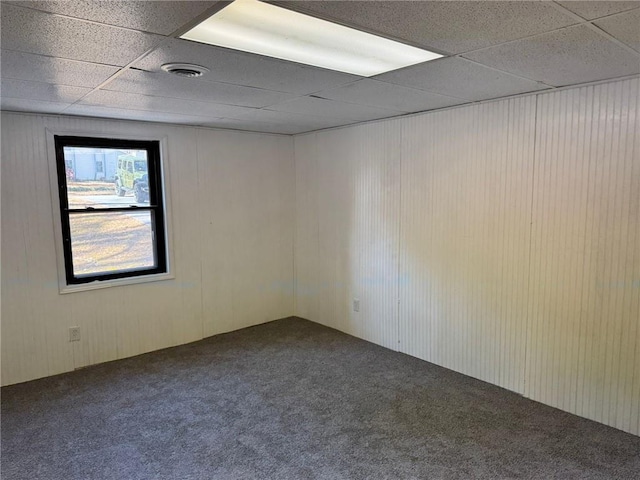 empty room featuring a paneled ceiling, visible vents, and carpet flooring