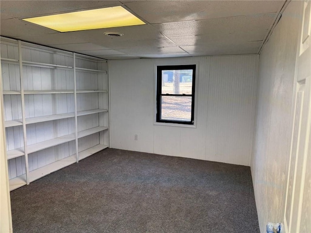 empty room featuring a paneled ceiling and carpet