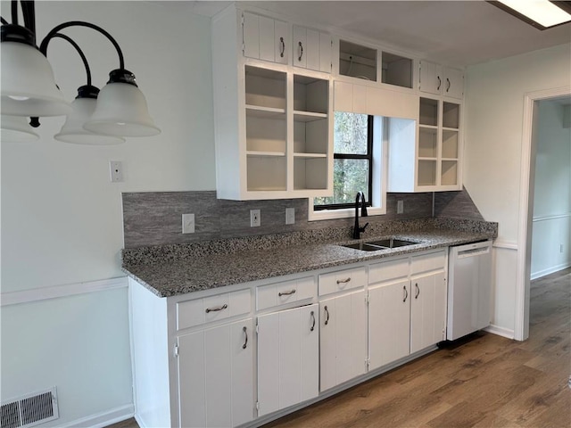 kitchen featuring dark wood-type flooring, a sink, visible vents, stainless steel dishwasher, and decorative backsplash