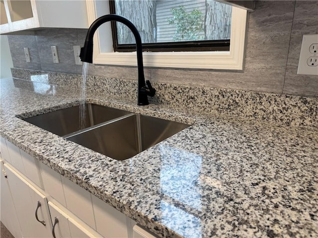 details featuring light stone counters, a sink, and white cabinets