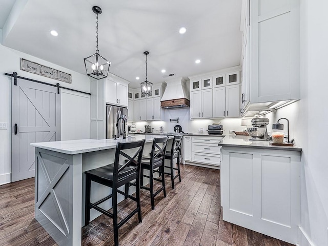 1170 Upper Sweetwater Trl SE, White, GA 30184 - kitchen with a barn door, stainless steel fridge, dark wood finished floors, custom range hood, and white cabinets