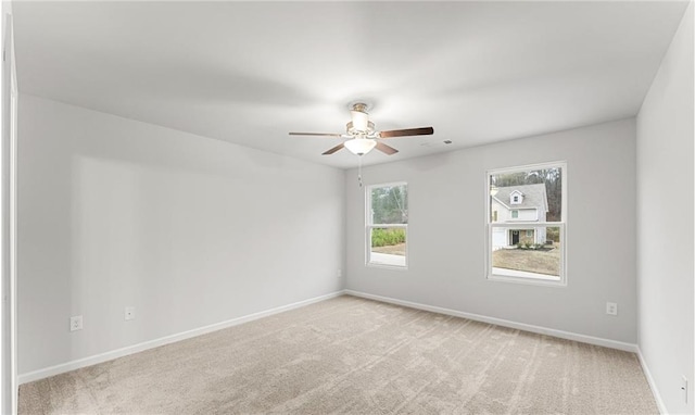 spare room featuring baseboards, ceiling fan, and light colored carpet