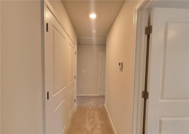 hall with baseboards and light colored carpet