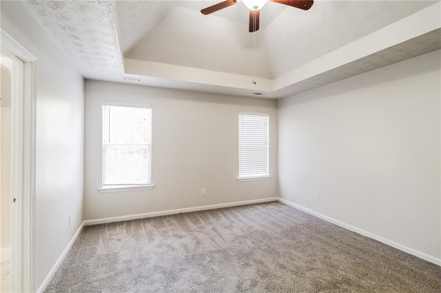spare room with a tray ceiling, baseboards, carpet, and a ceiling fan