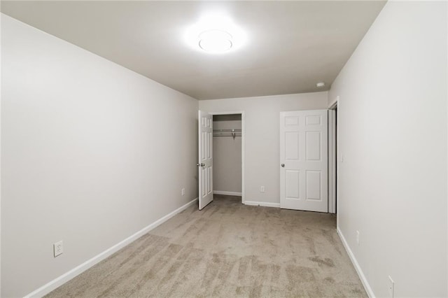unfurnished bedroom featuring baseboards, a closet, and light colored carpet