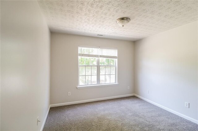 carpeted empty room with a textured ceiling