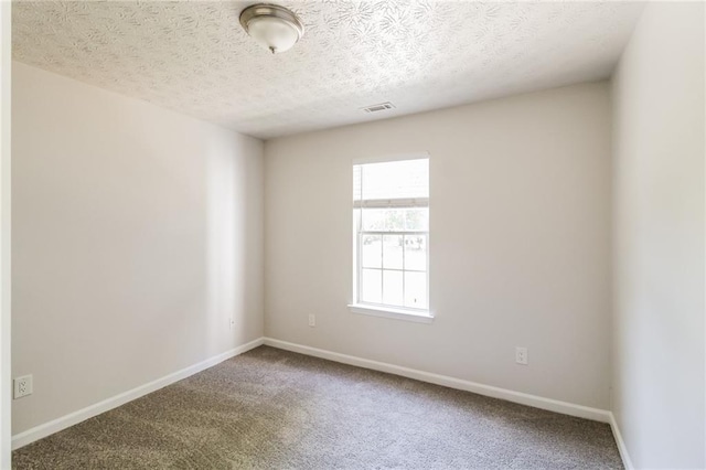 empty room featuring carpet flooring, a textured ceiling, baseboards, and visible vents