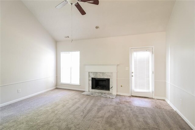 unfurnished living room featuring light carpet, a high end fireplace, ceiling fan, and vaulted ceiling