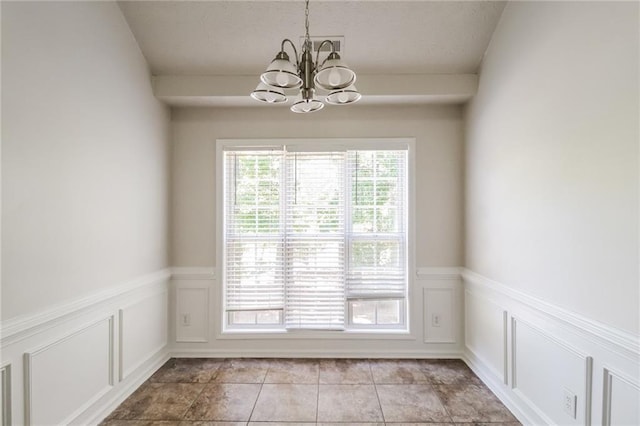 unfurnished dining area featuring a decorative wall, light tile patterned flooring, a chandelier, and a wainscoted wall