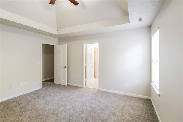 unfurnished room featuring light colored carpet, a raised ceiling, and ceiling fan