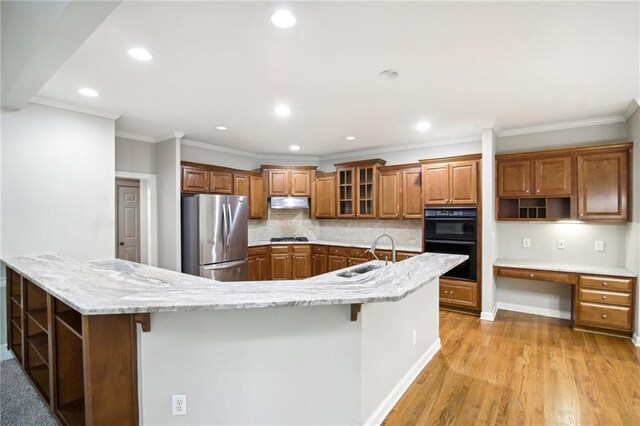 kitchen featuring appliances with stainless steel finishes, light hardwood / wood-style floors, decorative backsplash, sink, and a breakfast bar