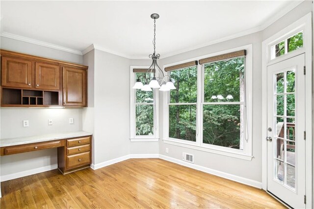 kitchen featuring light hardwood / wood-style flooring, built in desk, decorative light fixtures, and ornamental molding