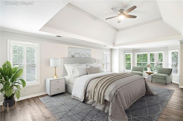 bedroom featuring ceiling fan, a raised ceiling, crown molding, and dark wood-type flooring