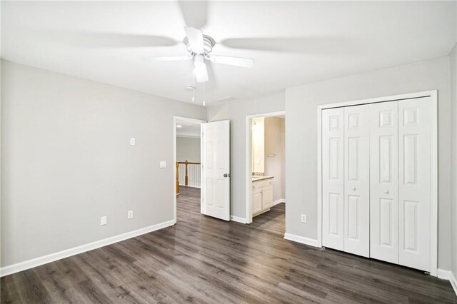 unfurnished bedroom featuring ceiling fan, a closet, ensuite bathroom, and dark wood-type flooring