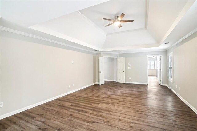 unfurnished bedroom with ceiling fan, a raised ceiling, dark hardwood / wood-style flooring, and ornamental molding