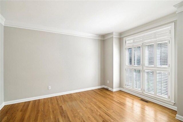 spare room featuring crown molding and light hardwood / wood-style flooring