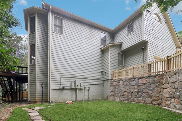 rear view of property with a wooden deck and a lawn