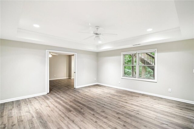 empty room featuring a tray ceiling, ceiling fan, and hardwood / wood-style flooring