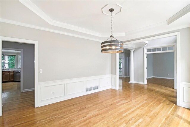 spare room with light hardwood / wood-style floors, a raised ceiling, and ornamental molding