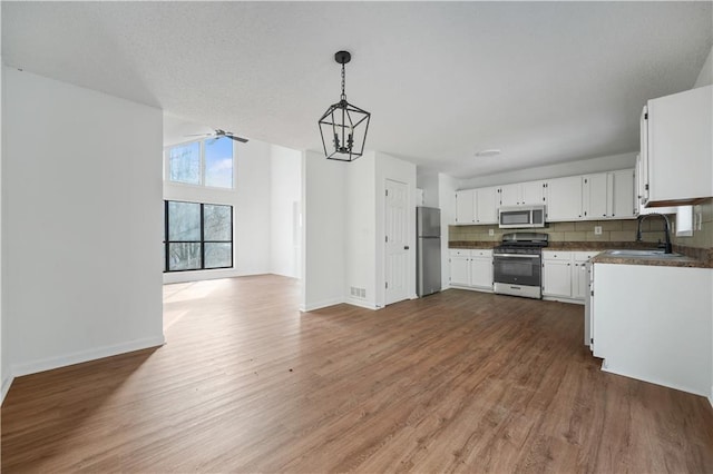 kitchen featuring a sink, appliances with stainless steel finishes, wood finished floors, and open floor plan