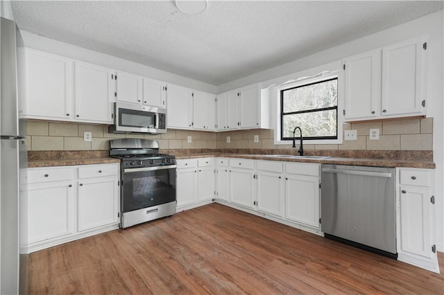 kitchen featuring dark wood-style flooring, dark countertops, appliances with stainless steel finishes, and a sink
