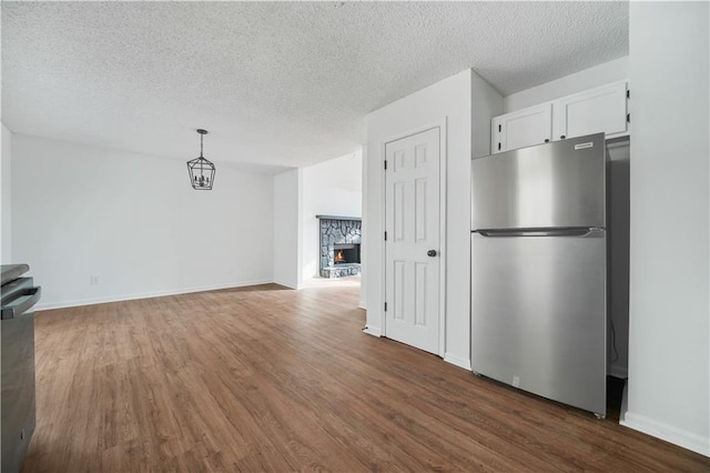 interior space with freestanding refrigerator, white cabinetry, a textured ceiling, and wood finished floors
