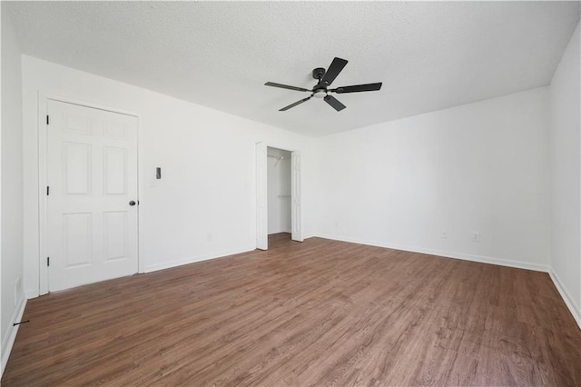 empty room featuring baseboards, ceiling fan, a textured ceiling, and wood finished floors