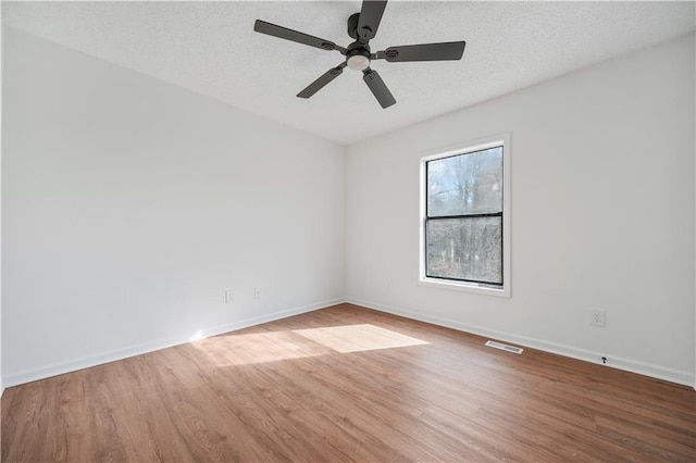 unfurnished room with baseboards, ceiling fan, wood finished floors, and visible vents