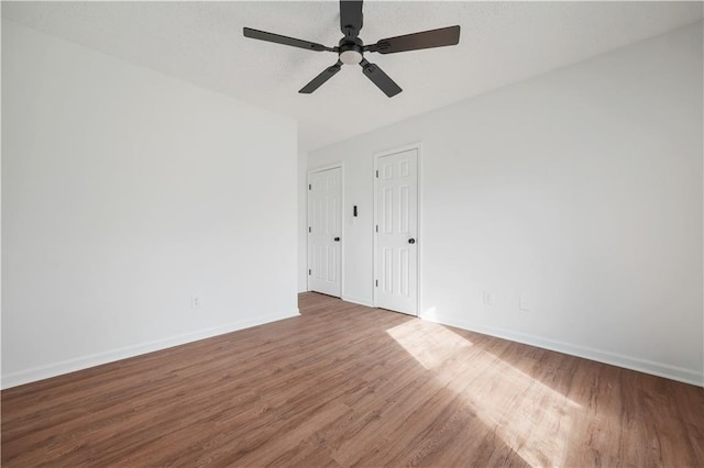 empty room featuring baseboards, a ceiling fan, and wood finished floors