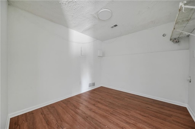 spare room featuring baseboards, a textured ceiling, wood finished floors, and visible vents