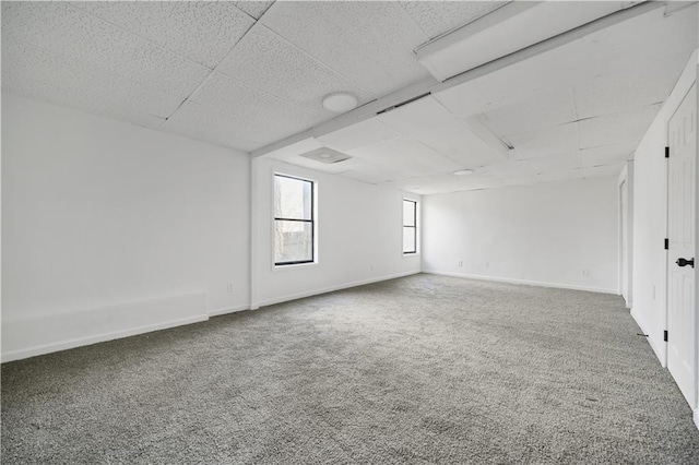 carpeted empty room featuring baseboards and a paneled ceiling