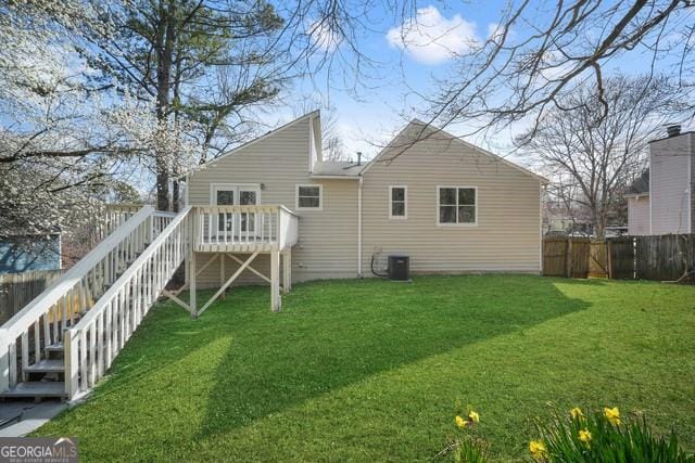 rear view of property featuring a deck, a fenced backyard, central AC unit, a yard, and stairway