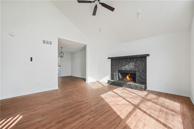 unfurnished living room featuring a fireplace, high vaulted ceiling, a ceiling fan, wood finished floors, and visible vents