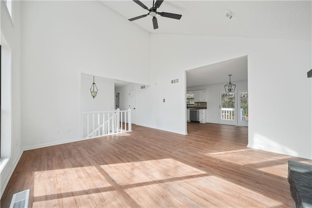 unfurnished living room with visible vents, wood finished floors, and high vaulted ceiling