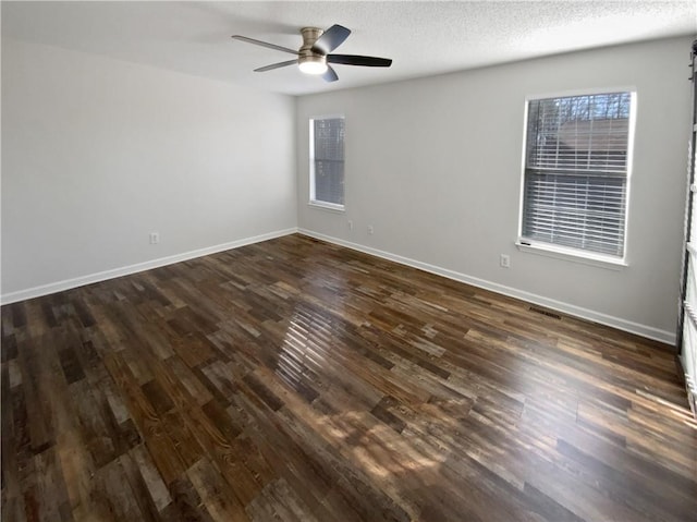 unfurnished room featuring visible vents, a textured ceiling, dark wood finished floors, baseboards, and ceiling fan