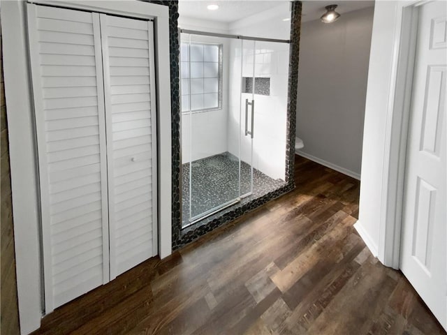 interior space with baseboards, toilet, recessed lighting, a stall shower, and wood finished floors