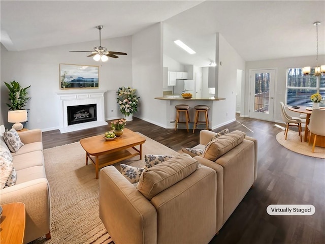 living area with dark wood finished floors, ceiling fan with notable chandelier, and lofted ceiling